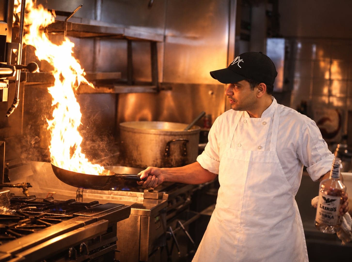 Chef Amrit Pal Singh at the range, flame rising from the pan in his hand